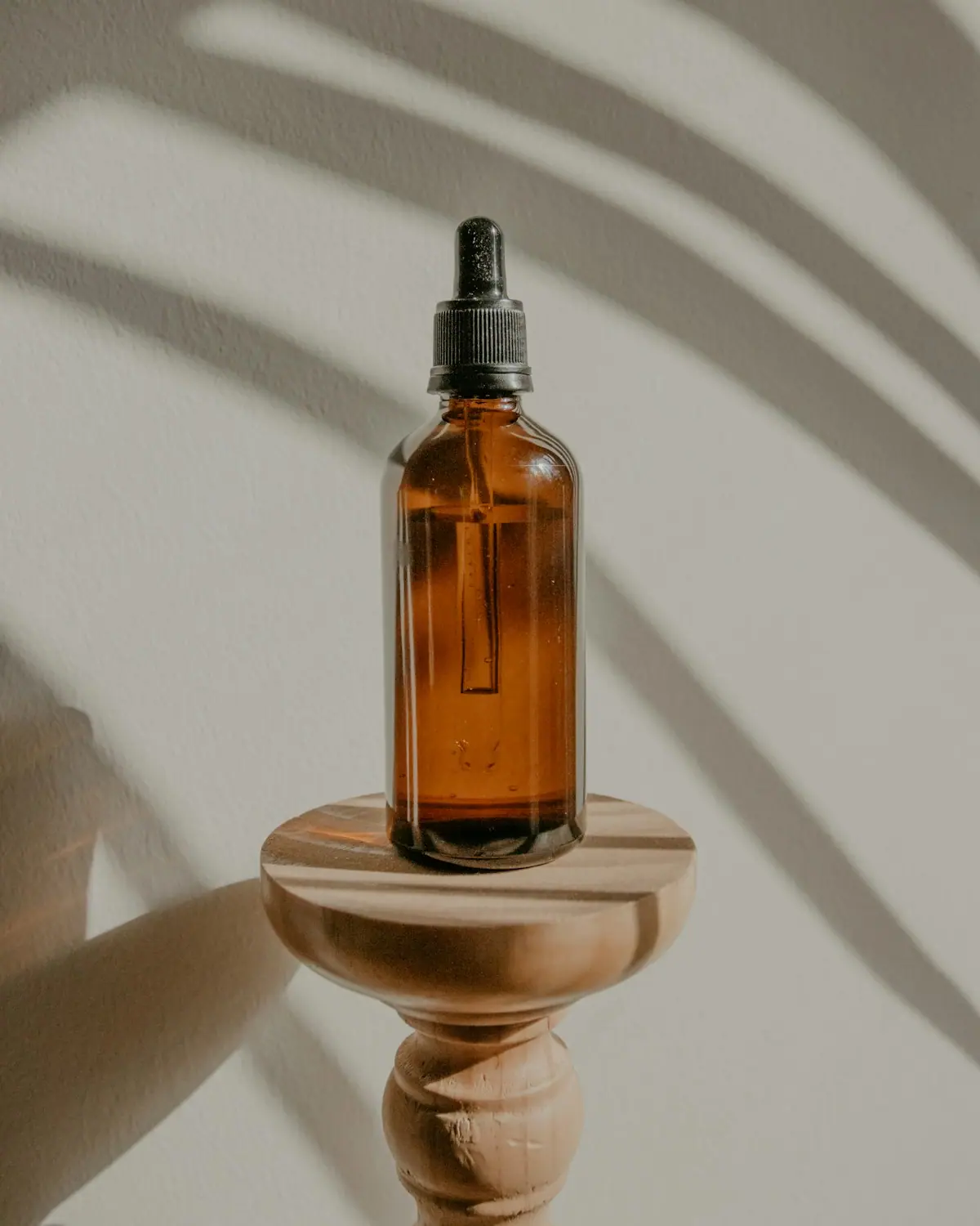 An amber glass bottle of After Water Replenishing Mist on a wooden stand